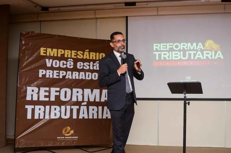 João Batista palestrando ao lado do banner “Empresário, você está preparado? Reforma Tributária”